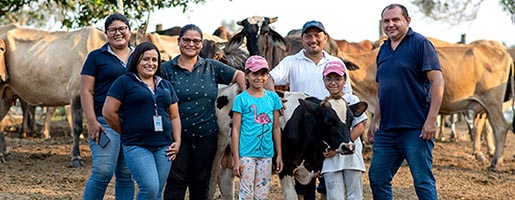Imagen de un grupo de personas posando para una foto en un entorno rural, con un rebaño de vacas de fondo